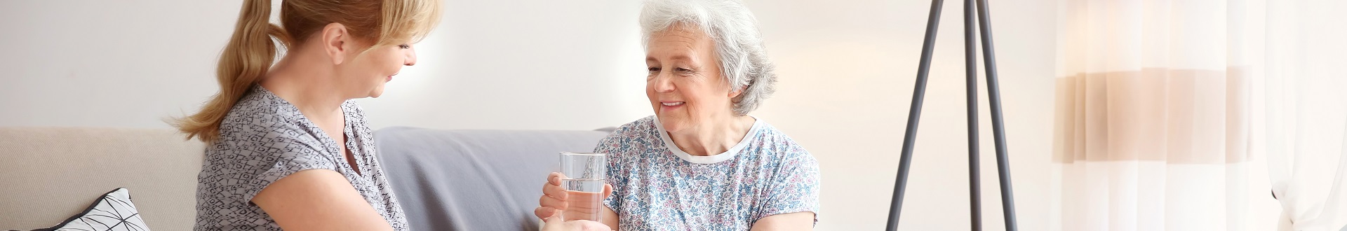 caregiver giving water to a senior woman