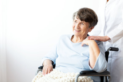 Happy grandmother in a wheelchair and caregiver supporting her