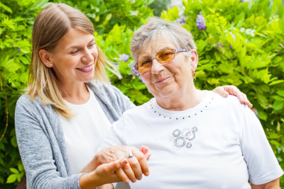 Picture of a happy senior lady wearing glasses with her beautiful granddaughter in the garden